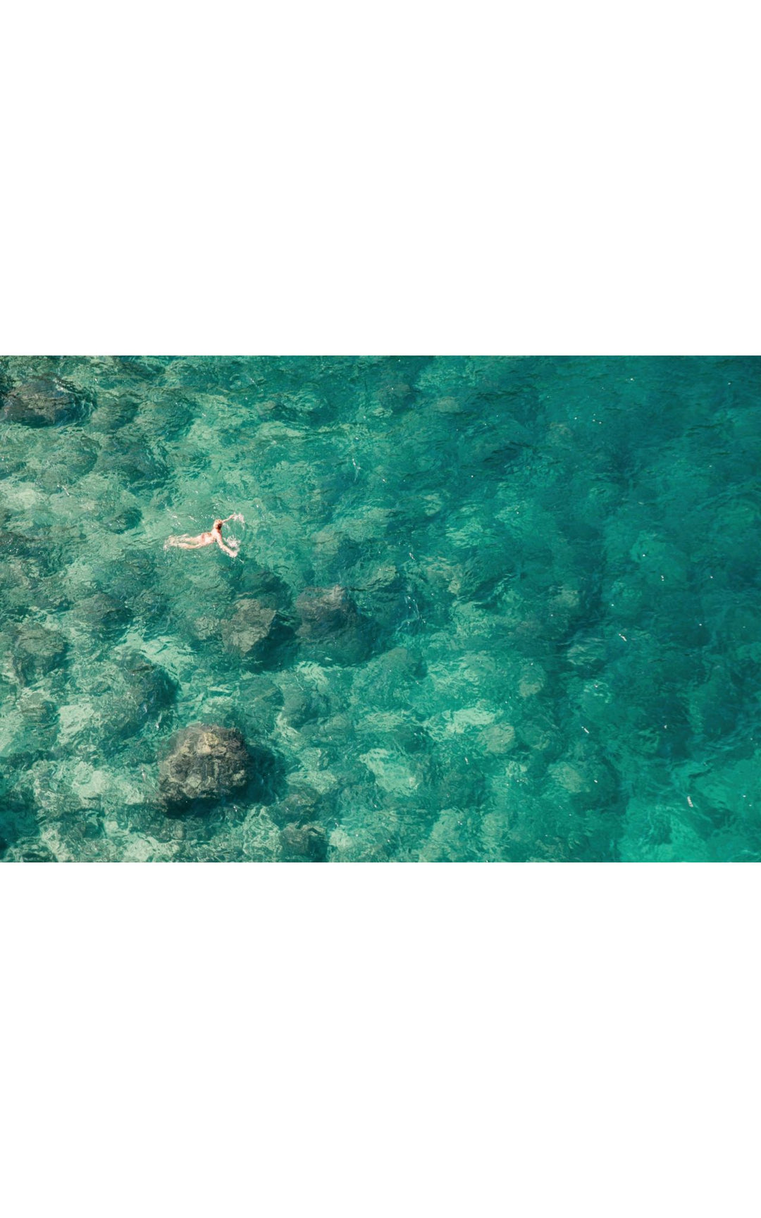Lone swimmer in vibrant turquoise waters.