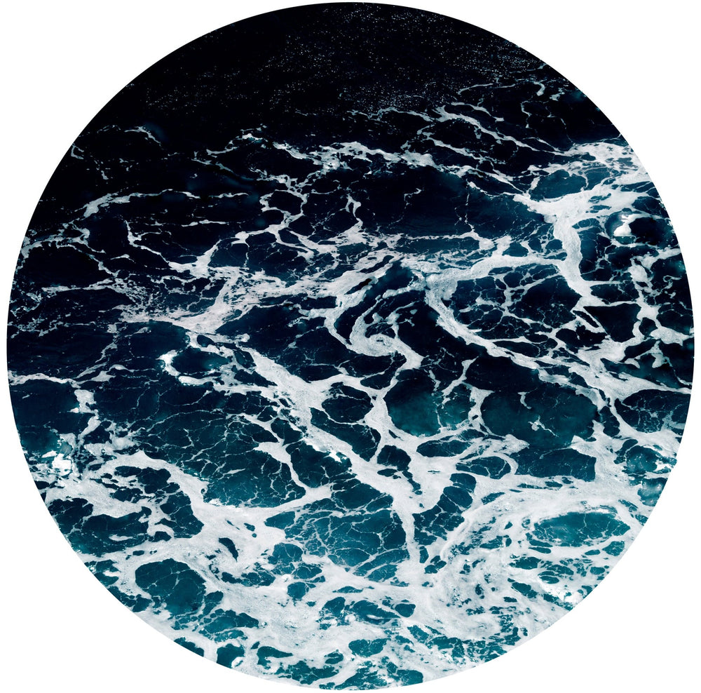 Circular photograph of whitecapped gentle waves marbling throughout the frame.