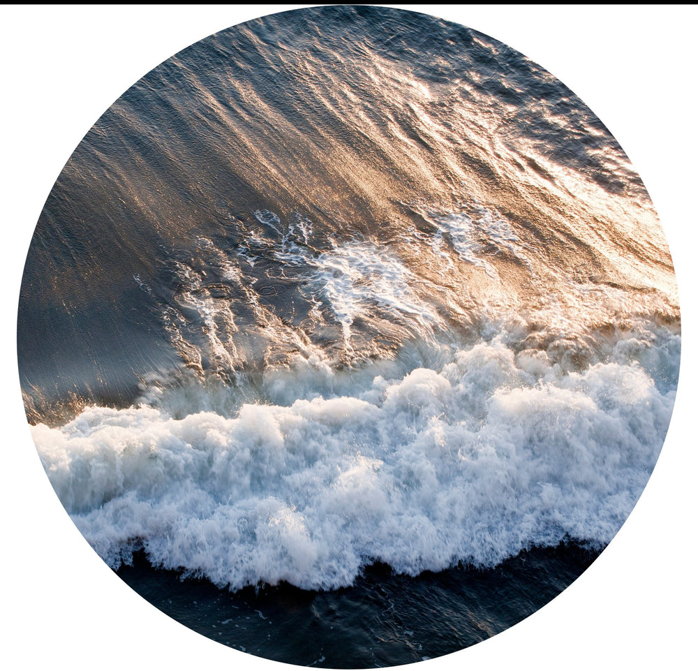 Aerial view close-up of wave crashing at sunset.