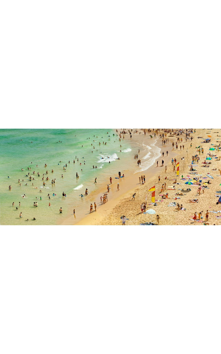Pacific Ocean beach scene. Beachgoers along emerald clear shoreline.