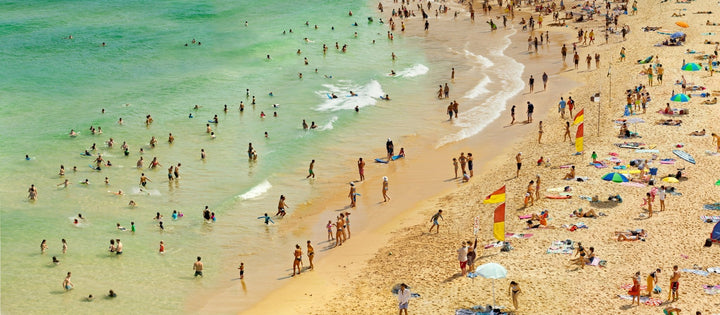 Pacific Ocean beach scene. Beachgoers along emerald clear shoreline.