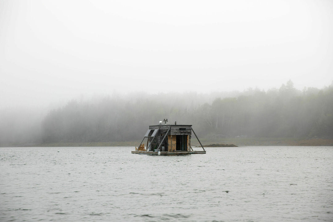 Photograph pf houseboat floating on a foggy Maine lake.