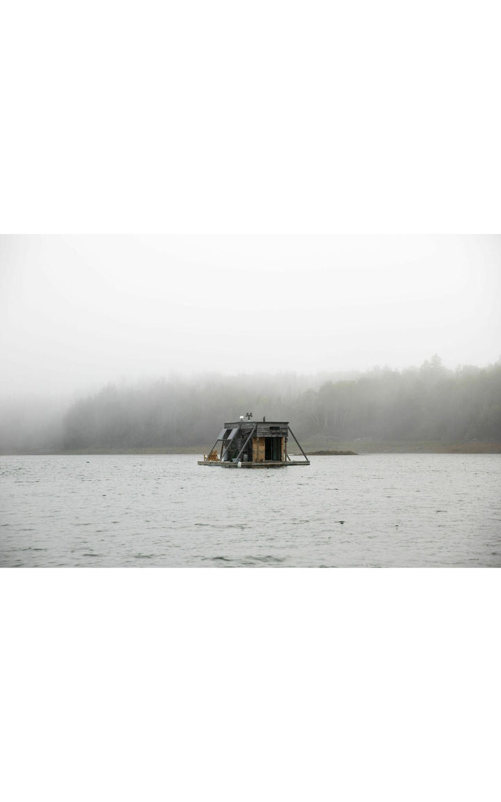 Photograph pf houseboat floating on a foggy Maine lake.