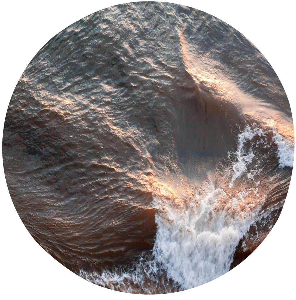 Gentle ripples evolve into a whitecapped wave during golden hour.