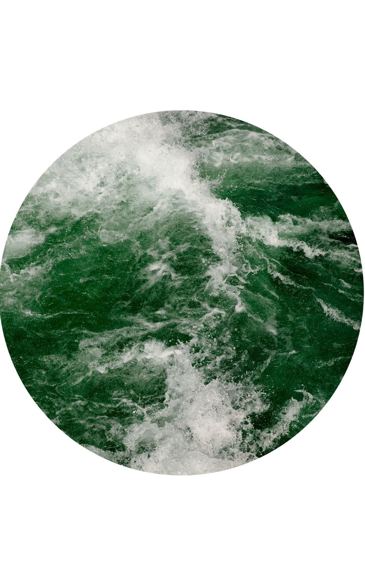 Emerald green waters and energetic waves spraying throughout a round photograph.