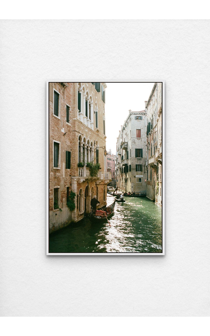 Photograph of a sunlit canal lined with architecture and gondolas.