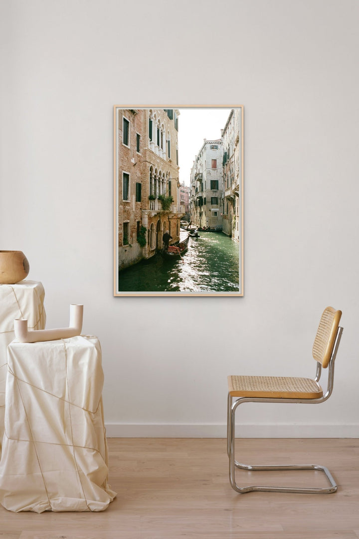 Photograph of a sunlit canal lined with architecture and gondolas.