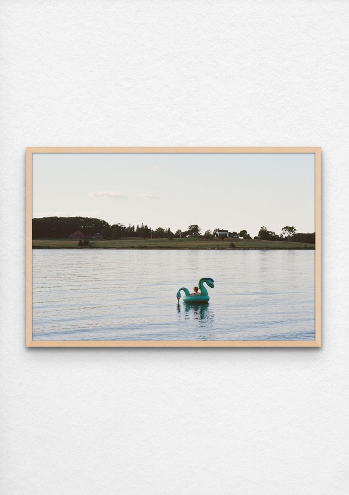 Photograph of woman floating on lake near a lake house in Maine framed in maple and installed - Artly International